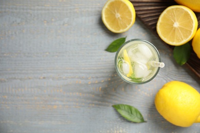 Photo of Cool freshly made lemonade and fruits on grey wooden table, flat lay. Space for text