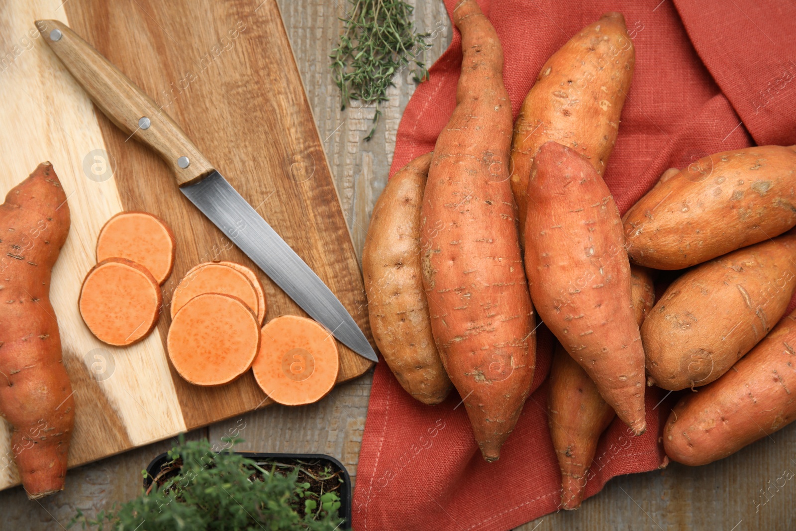 Photo of Sweet potatoes and thyme on wooden table, flat lay