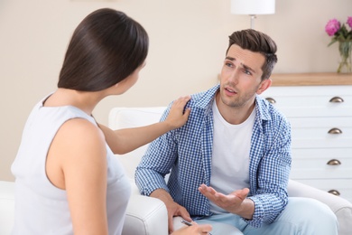 Depressed young man having appointment with psychologist in office