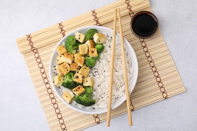 Bowl of rice with fried tofu and broccoli on white table, top view