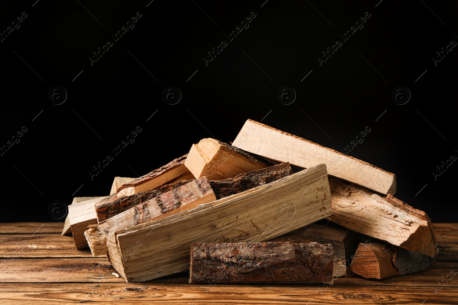 Photo of Cut firewood on table against black background