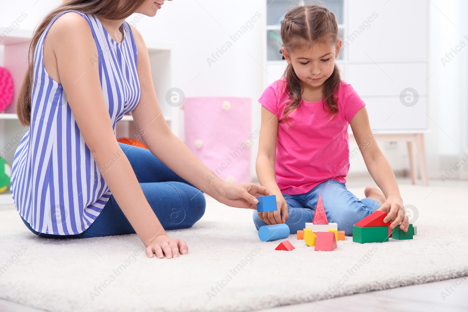 Photo of Woman and her child playing together with colorful blocks at home