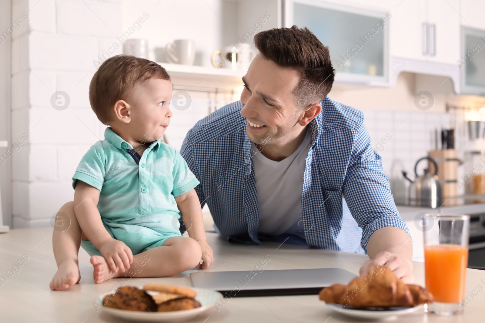 Photo of Young father with his cute little son in kitchen