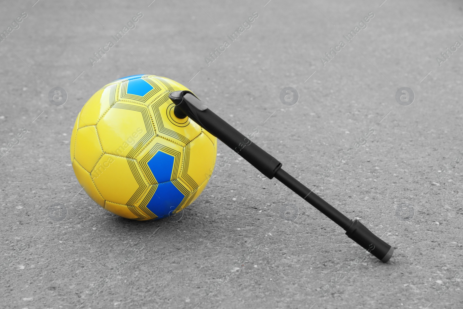 Photo of Soccer ball with manual pump inflator on asphalt