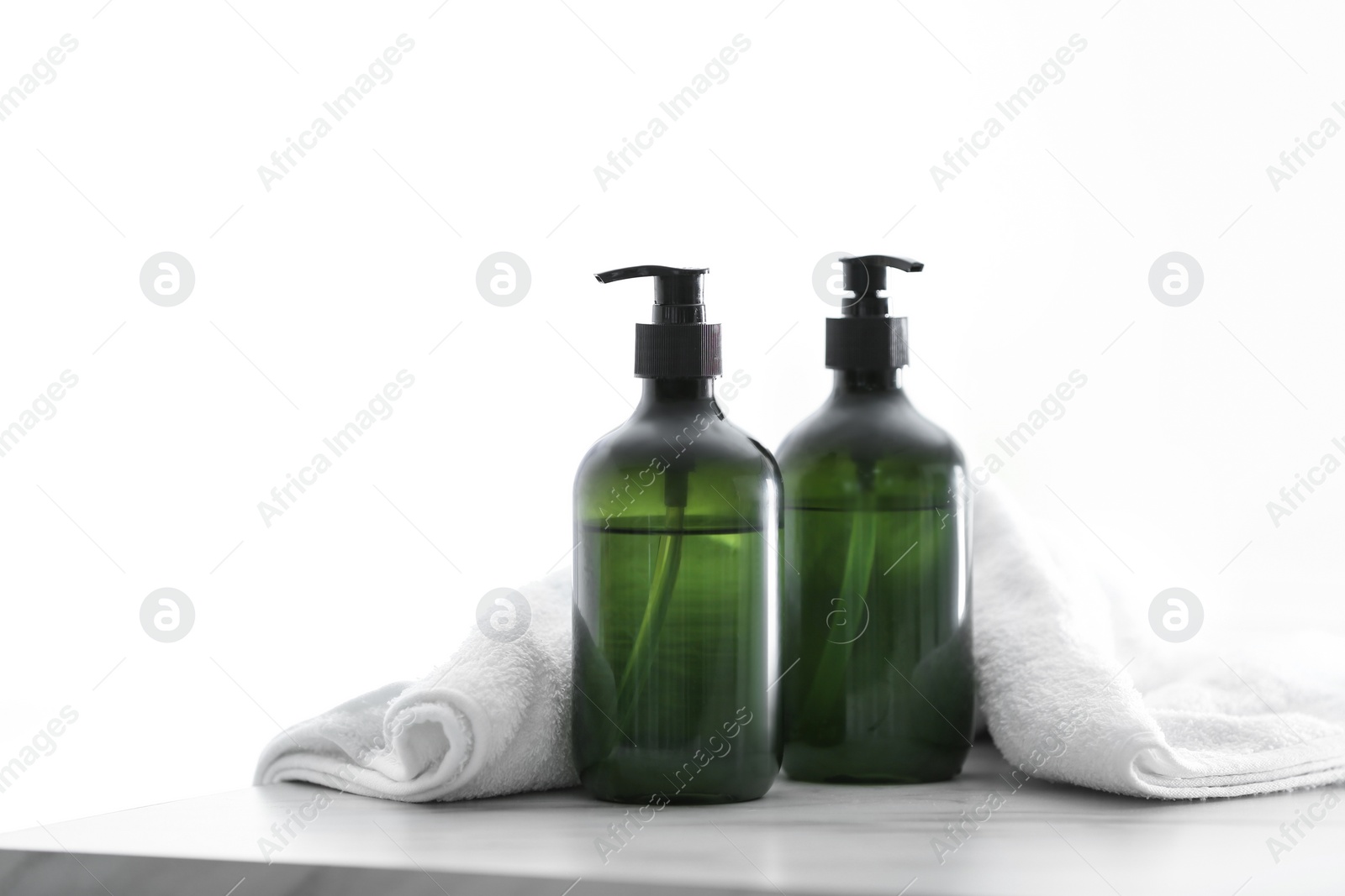 Photo of Soap dispensers and clean towel on white table