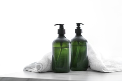 Photo of Soap dispensers and clean towel on white table