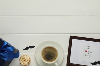 Photo of Father's day celebration. Flat lay composition of card with phrase I Love You Daddy and cup of aromatic coffee on white wooden table. Space for text
