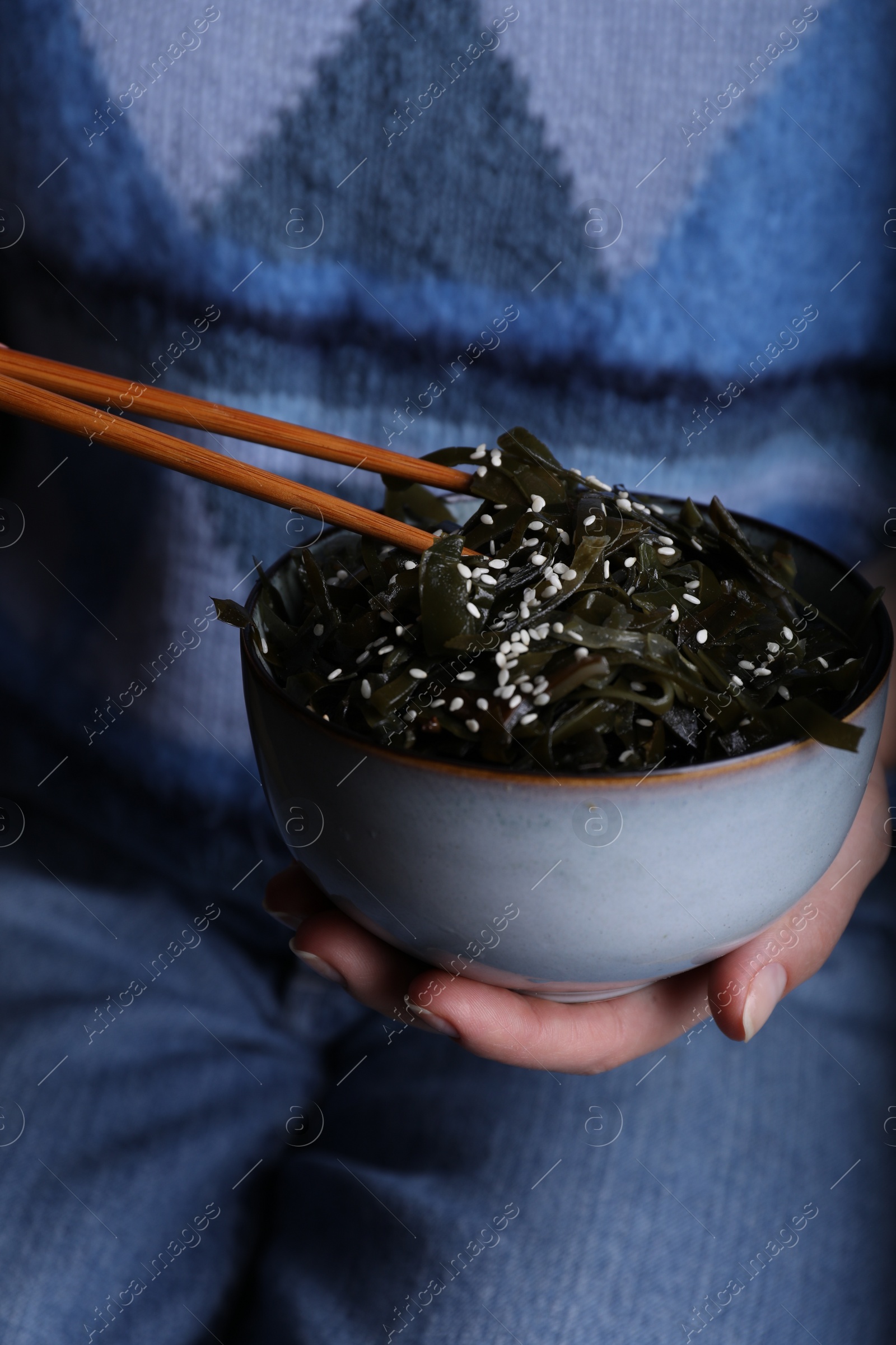 Photo of Woman eating fresh laminaria (kelp) seaweed, closeup