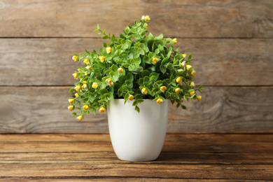 Photo of Artificial plant in white flower pot on wooden table