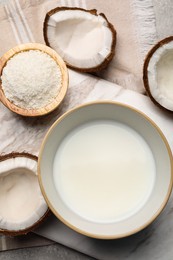 Photo of Bowl of delicious coconut milk, flakes and coconuts on light grey table, flat lay