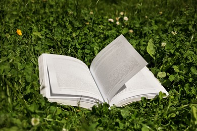 Photo of Open book in beautiful green meadow on sunny day