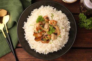 Photo of Delicious rice with mushrooms and parsley served on wooden table, flat lay