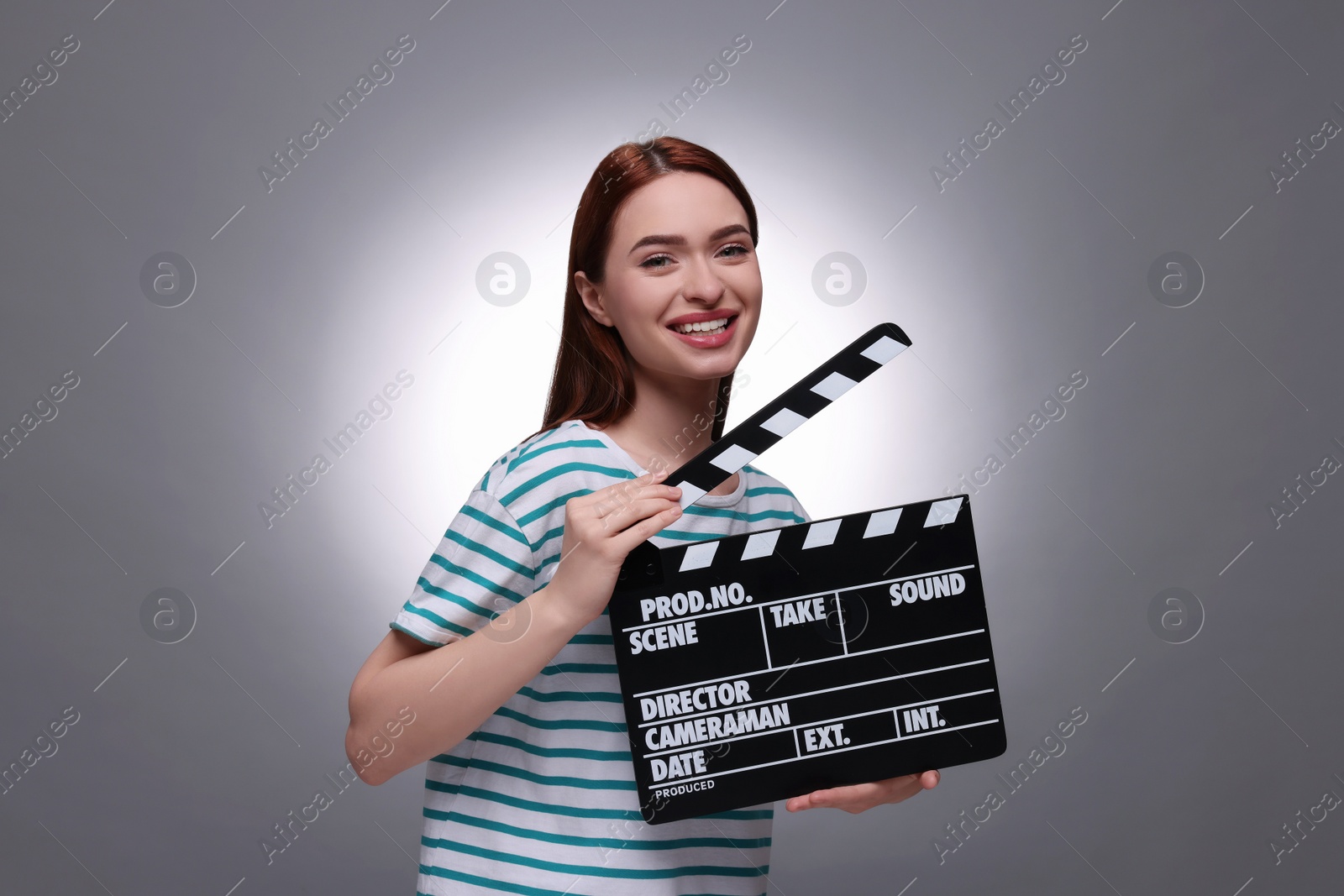 Photo of Happy actress with clapperboard on grey background. Film industry