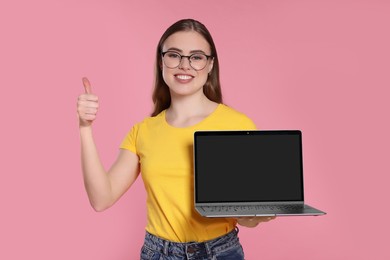 Photo of Happy woman with laptop showing thumb up on pink background