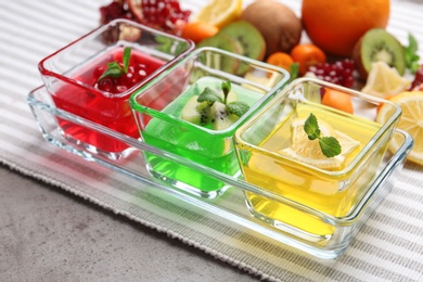 Tray with glass bowls of tasty jelly desserts on table