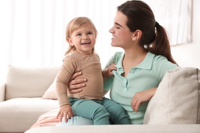 Photo of Mother with her cute little daughter on sofa at home