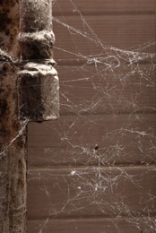 Photo of Cobweb near wall and rusty pipes of water supply indoors