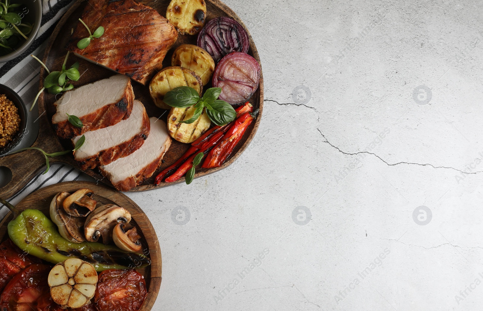 Photo of Delicious grilled meat and vegetables served on light grey table, flat lay. Space for text