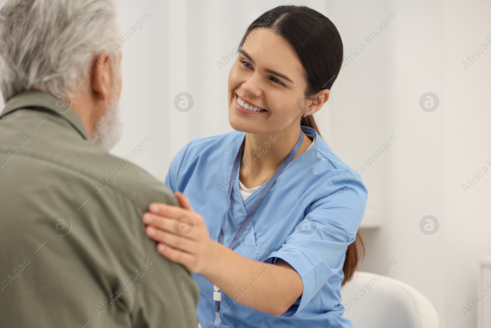 Photo of Smiling nurse supporting elderly patient in hospital