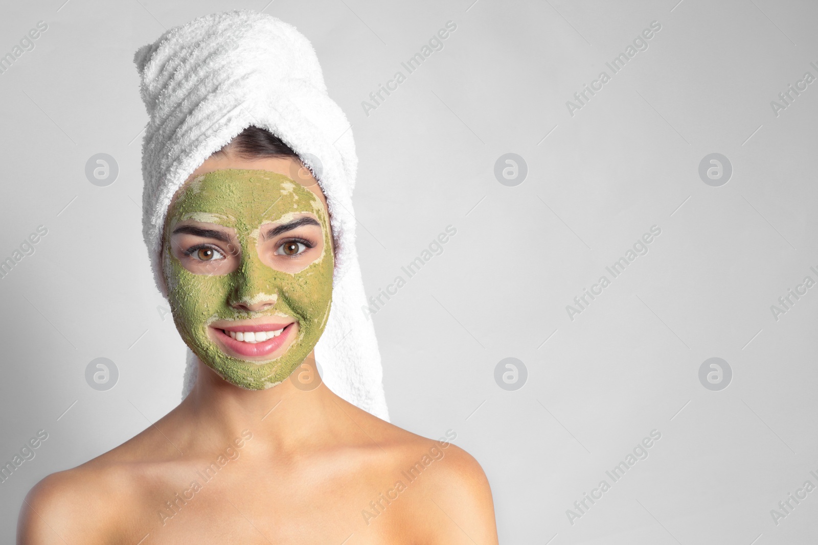 Photo of Young woman with clay mask on her face against light background, space for text. Skin care