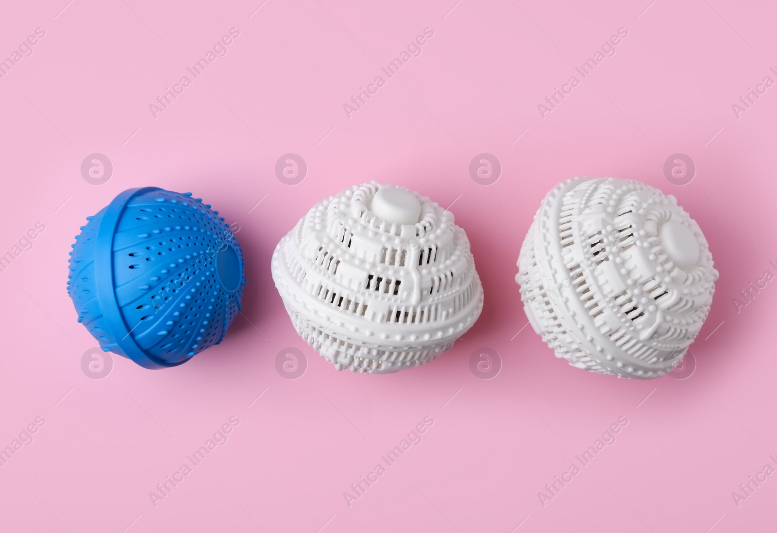 Photo of Dryer balls for washing machine on pink background, flat lay