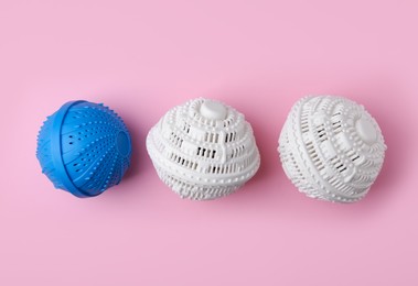 Photo of Dryer balls for washing machine on pink background, flat lay