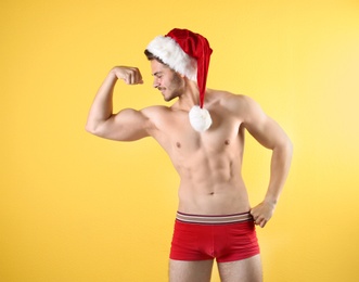 Photo of Shirtless young Santa Claus with sexy body on color background