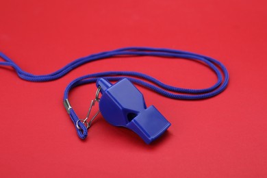 Photo of One blue whistle with cord on red background