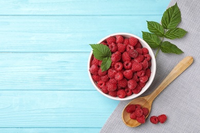 Bowl and spoon with ripe aromatic raspberries on wooden table, top view