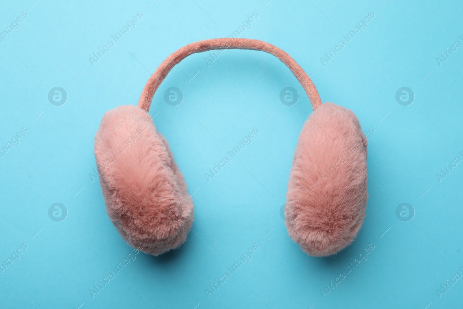 Photo of Stylish warm earmuffs on light blue background, top view