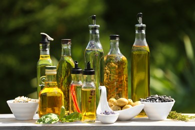 Photo of Different cooking oils and ingredients on wooden table against blurred green background