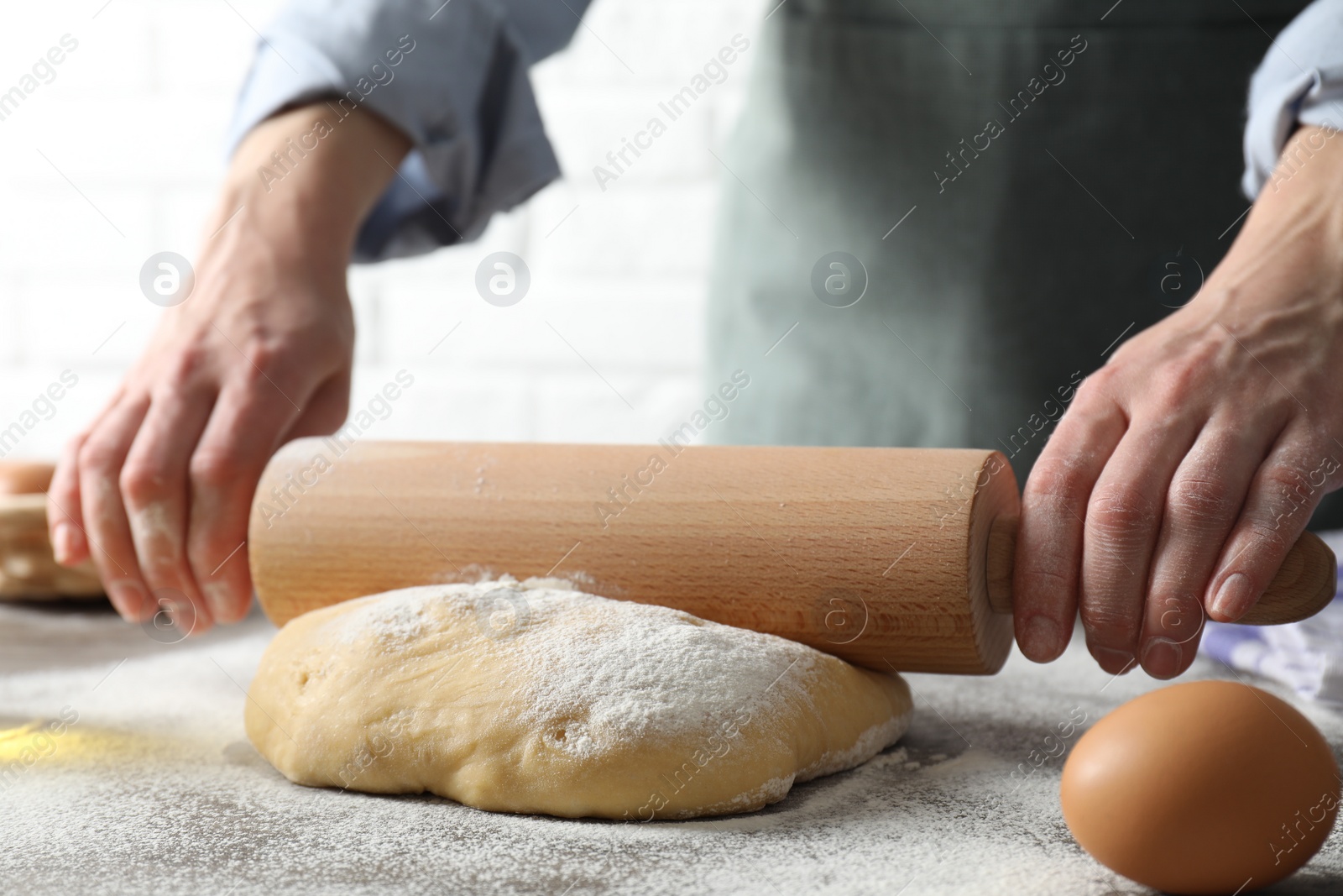 Photo of Woman rolling raw dough at table, closeup