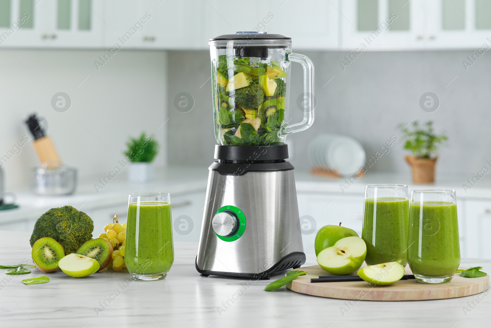 Photo of Delicious fresh smoothie and blender with ingredients on white marble table in kitchen