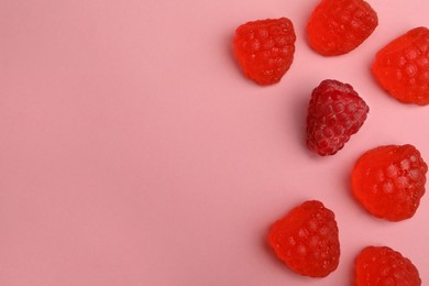 Delicious gummy raspberry candies and fresh fruit on pink background, flat lay. Space for text