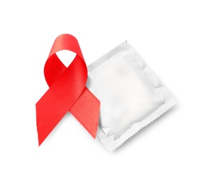 Photo of Red ribbon and condom isolated on white, top view. AIDS disease awareness