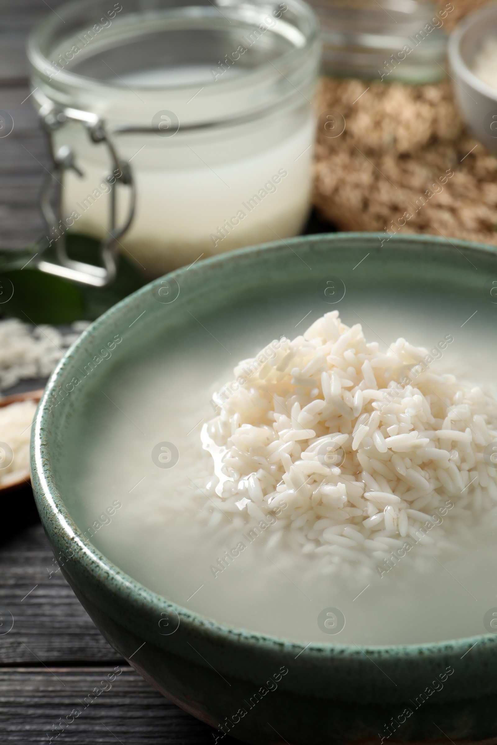 Photo of Bowl with rice soaked in water on wooden table, closeup