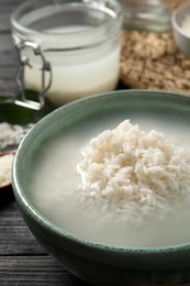 Photo of Bowl with rice soaked in water on wooden table, closeup