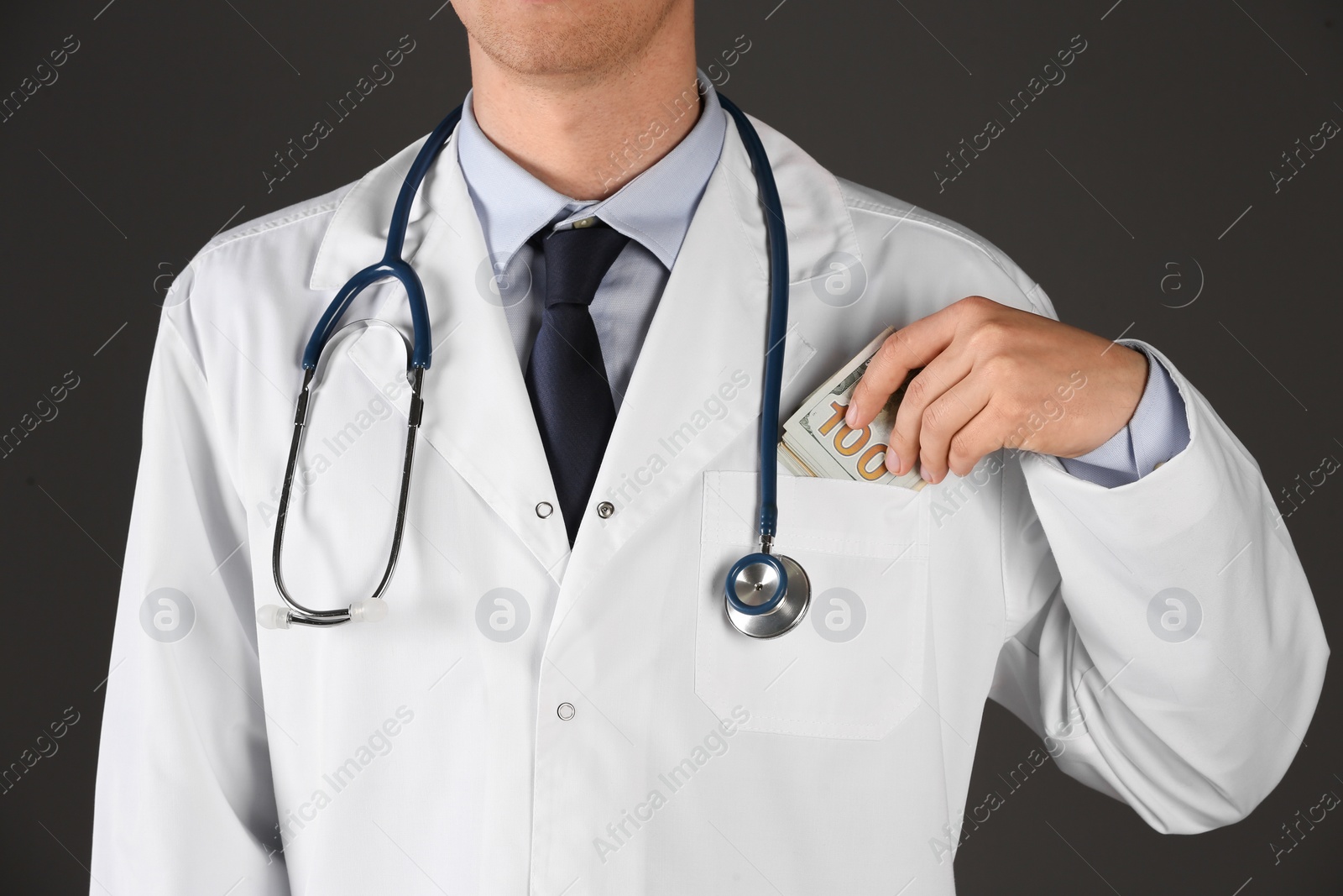 Photo of Doctor putting bribe into pocket on black background, closeup. Corruption in medicine