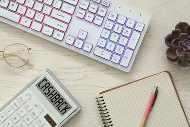 Image of Calculator with word Cashback, computer keyboard, notebook, pen and houseplant on wooden table, flat lay