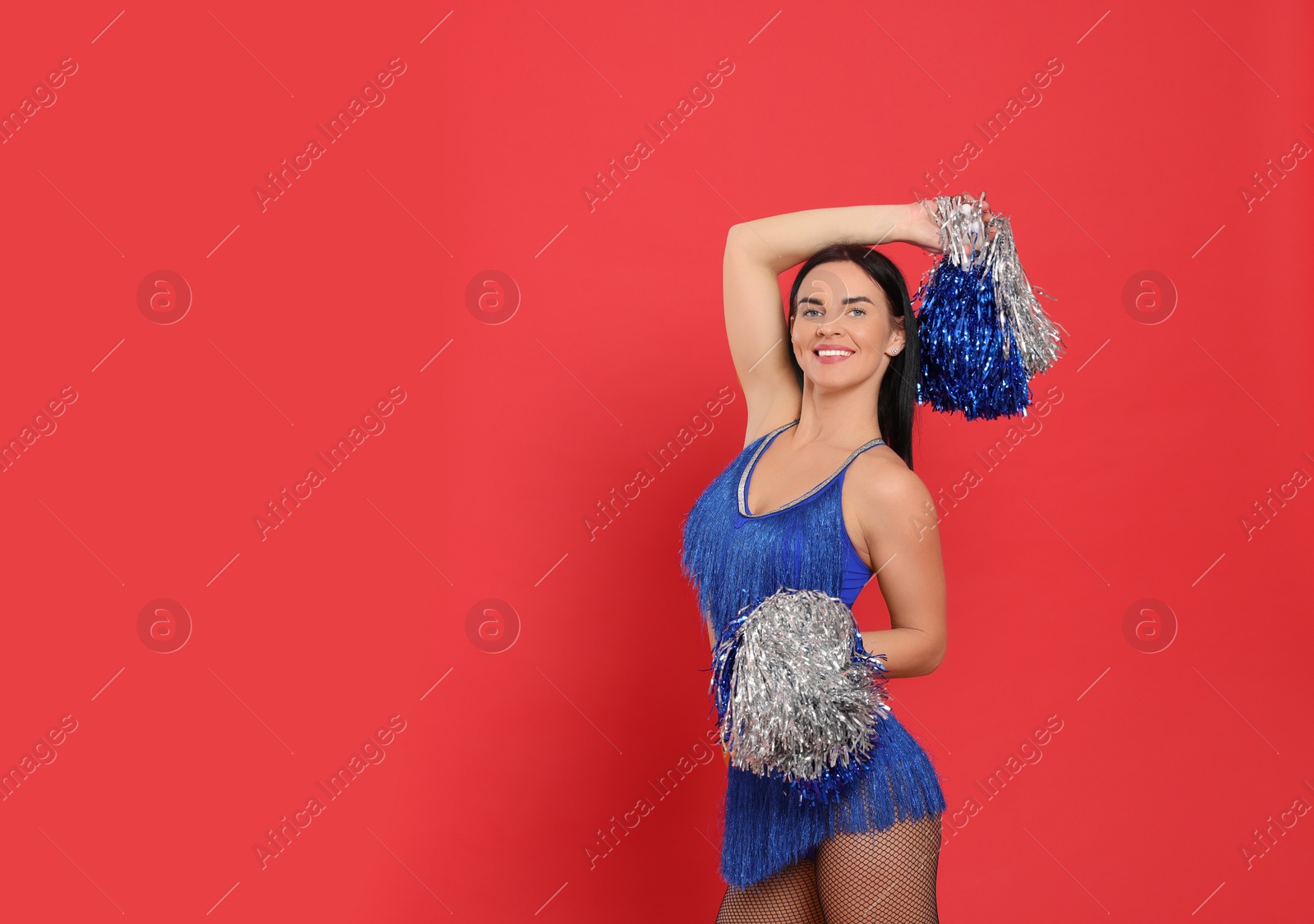 Photo of Beautiful cheerleader in costume holding pom poms on red background. Space for text