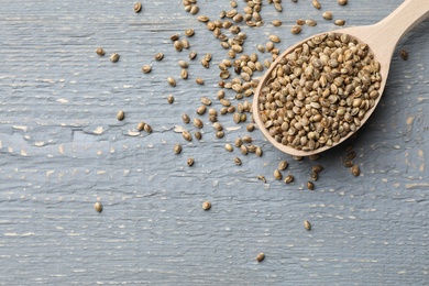 Photo of Organic hemp seeds on grey wooden table, top view. Space for text