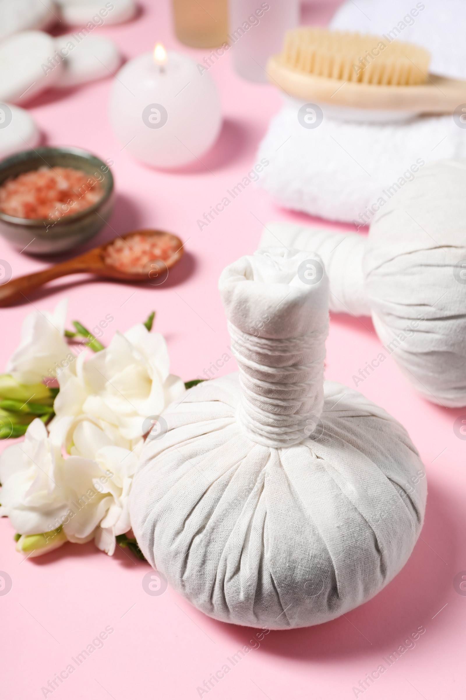 Photo of Herbal massage bags and other spa products on pink background, closeup