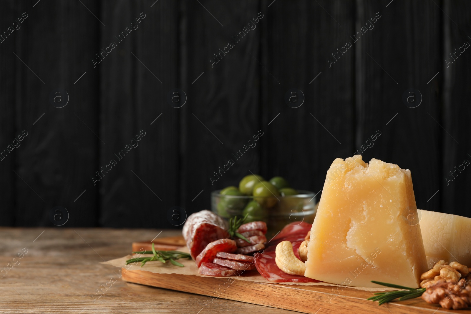 Photo of Snack platter with parmesan cheese on wooden table. Space for text