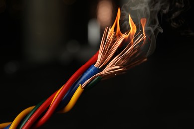 Image of Electrical wire burning on dark background, closeup