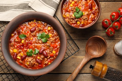 Photo of Tasty chili con carne served on wooden table, flat lay