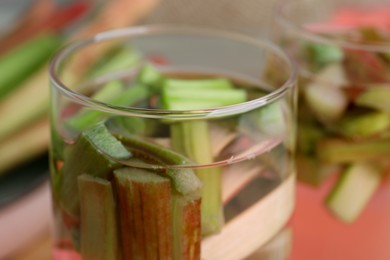 Photo of Glass of tasty rhubarb cocktail on blurred background, closeup