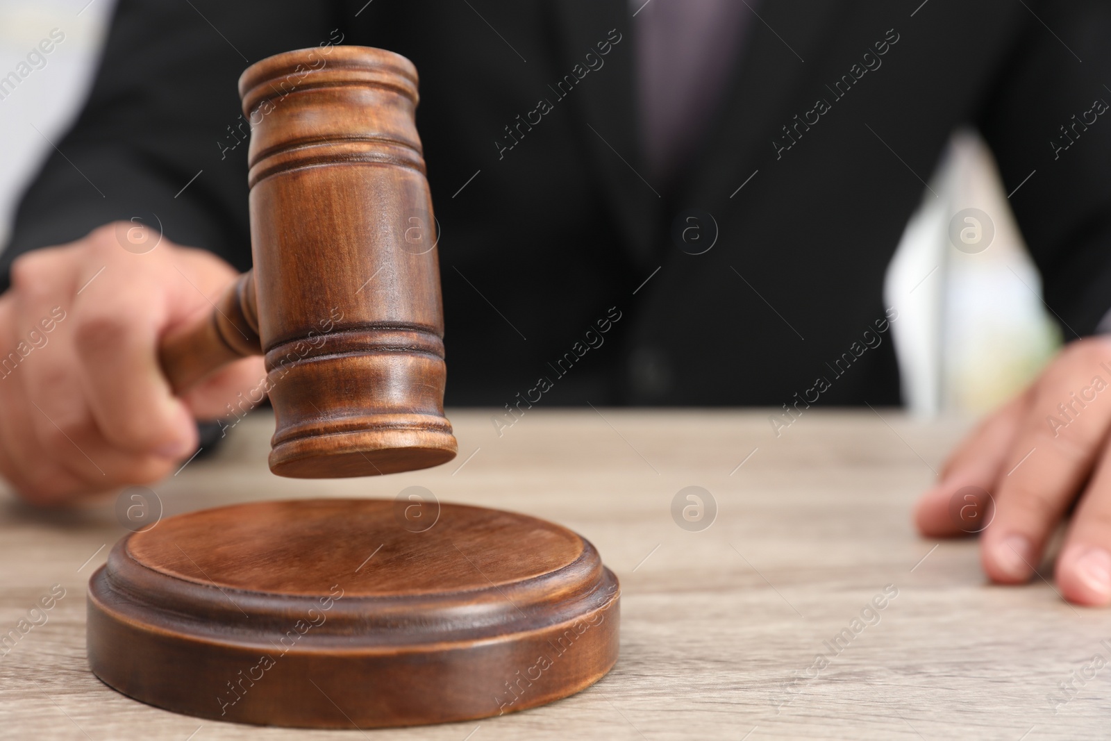 Photo of Judge with gavel at wooden table indoors, closeup. Criminal law