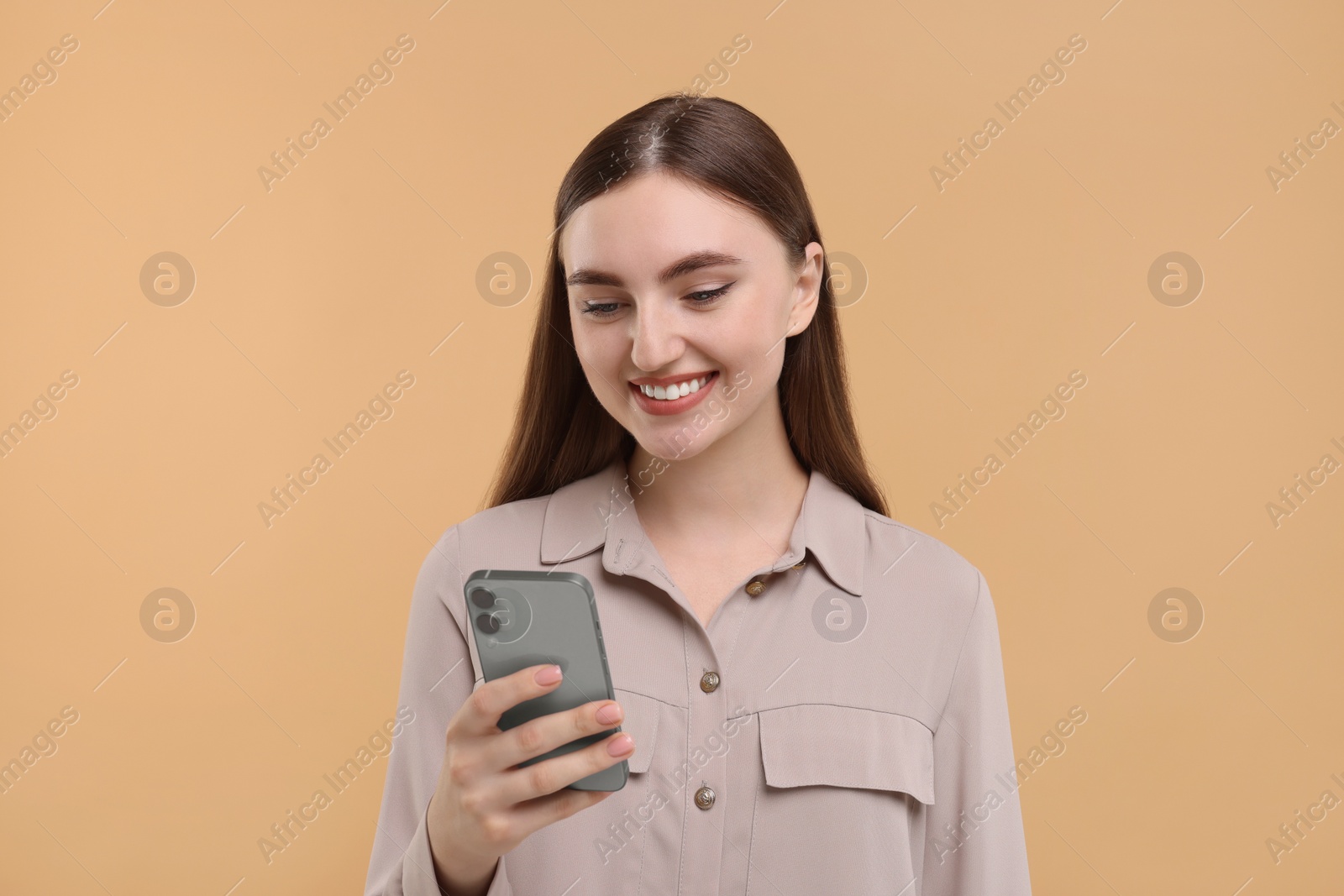 Photo of Smiling woman using smartphone on beige background