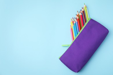 Photo of Many colorful pencils in pencil case on light blue background, top view. Space for text