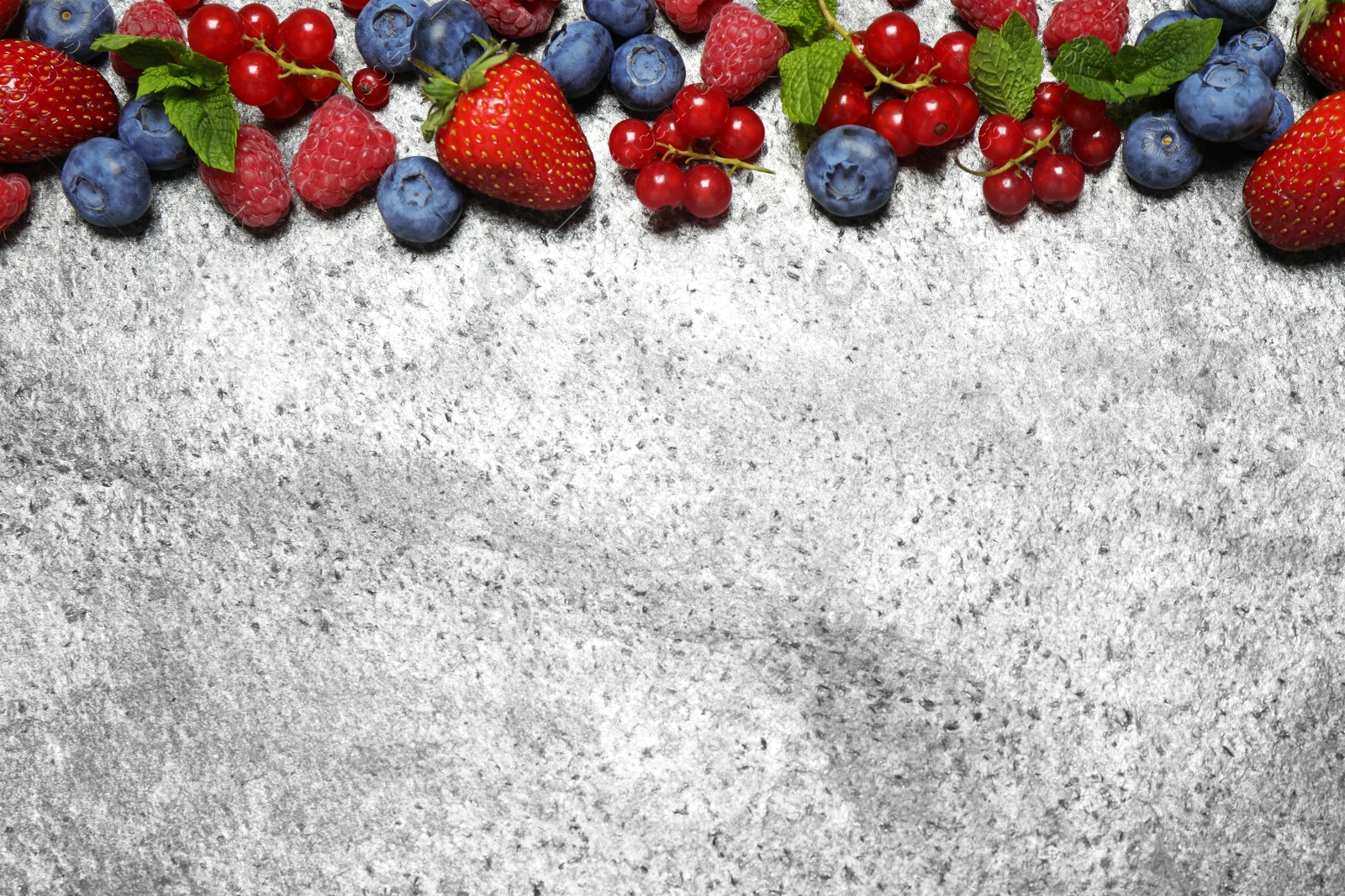 Photo of Different fresh berries on grey background, flat lay. Space for text